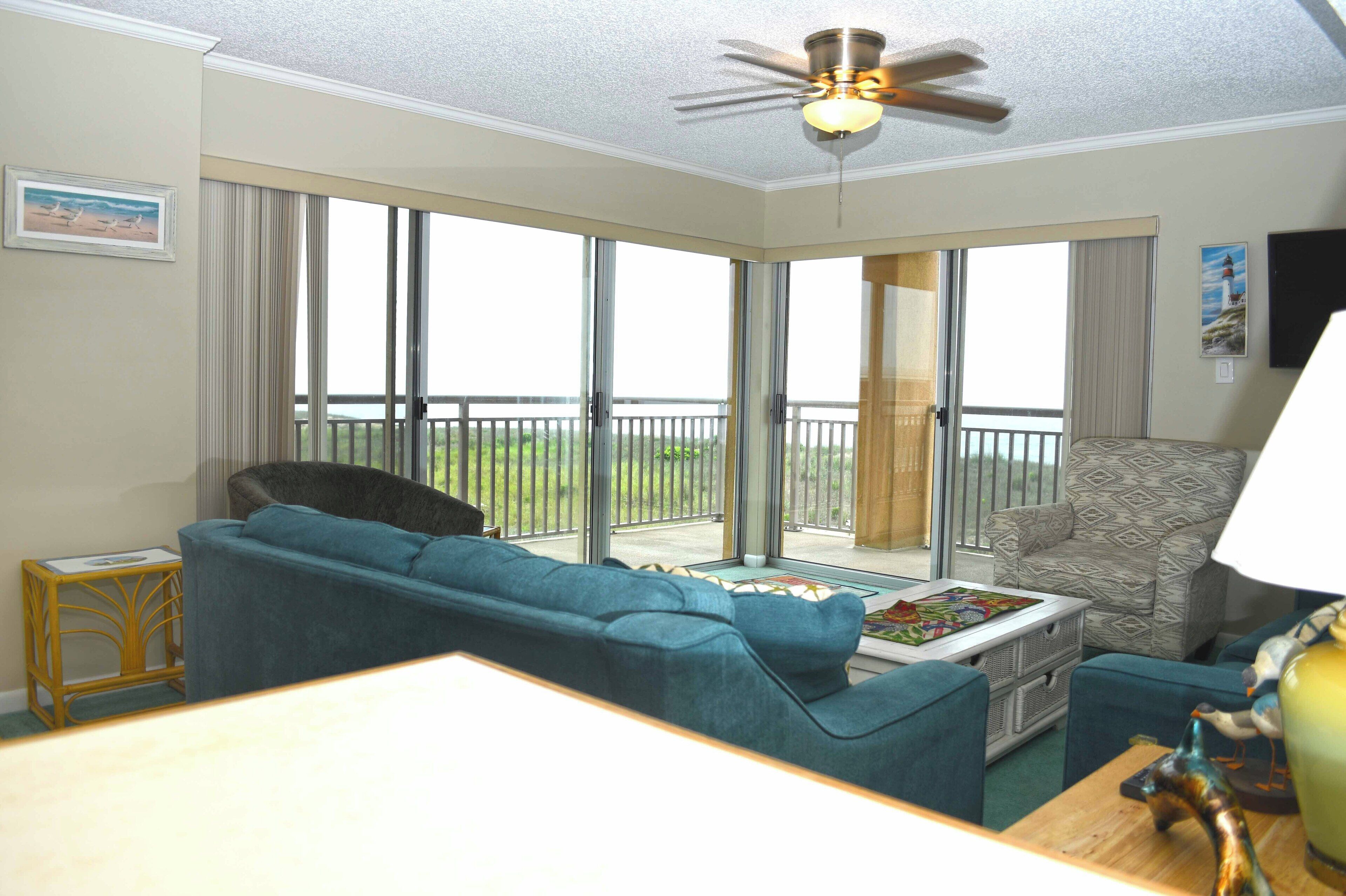 A living room with a blue sofa, a patterned armchair, and a coffee table with a decorative item.