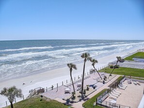 A beachside hotel with a patio area, palm trees, and ocean views.