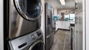 A modern kitchen with stainless steel appliances, a built-in washer and dryer, and a view to the outside.