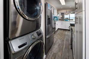 Une cuisine moderne dotée d’appareils électroménagers en acier inoxydable, d’un lave-linge intégré et offrant une vue sur l’extérieur.