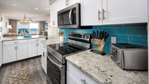 A modern kitchen with white cabinets, a stainless steel microwave, a built-in oven, and a granite countertop.