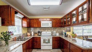 A kitchen with wooden cabinets, a white microwave, and a granite countertop.