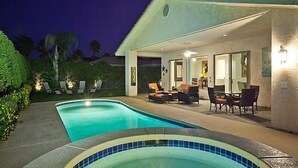 A swimming pool with lounge chairs and a dining area with tables and chairs.
