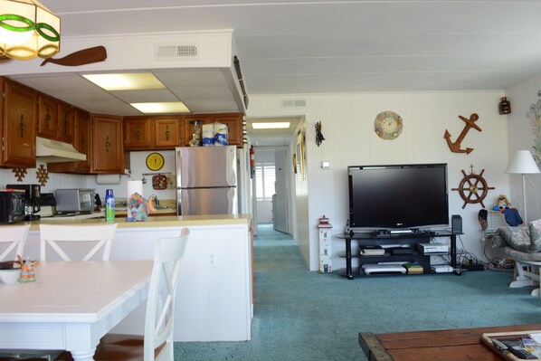 Un espacio habitable compacto con cocina, comedor y zona de entretenimiento con televisor.