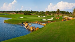 Ein Golfplatz mit einem Wassengebiet, Sandbunkern und einem gepflegten Grün.
