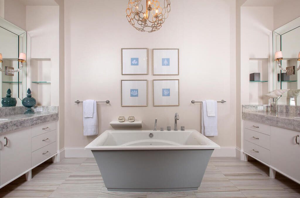 Ein modernes Badezimmer mit einer freistehenden Badewanne, zwei Waschtischspiegeln und gerahmten Kunstwerken an der Wand.