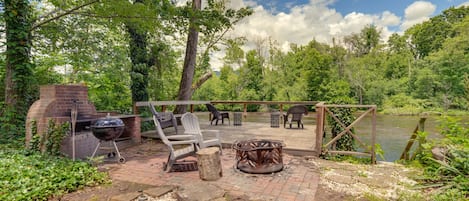 An outdoor patio area with a grill, seating, and a view of a lake.