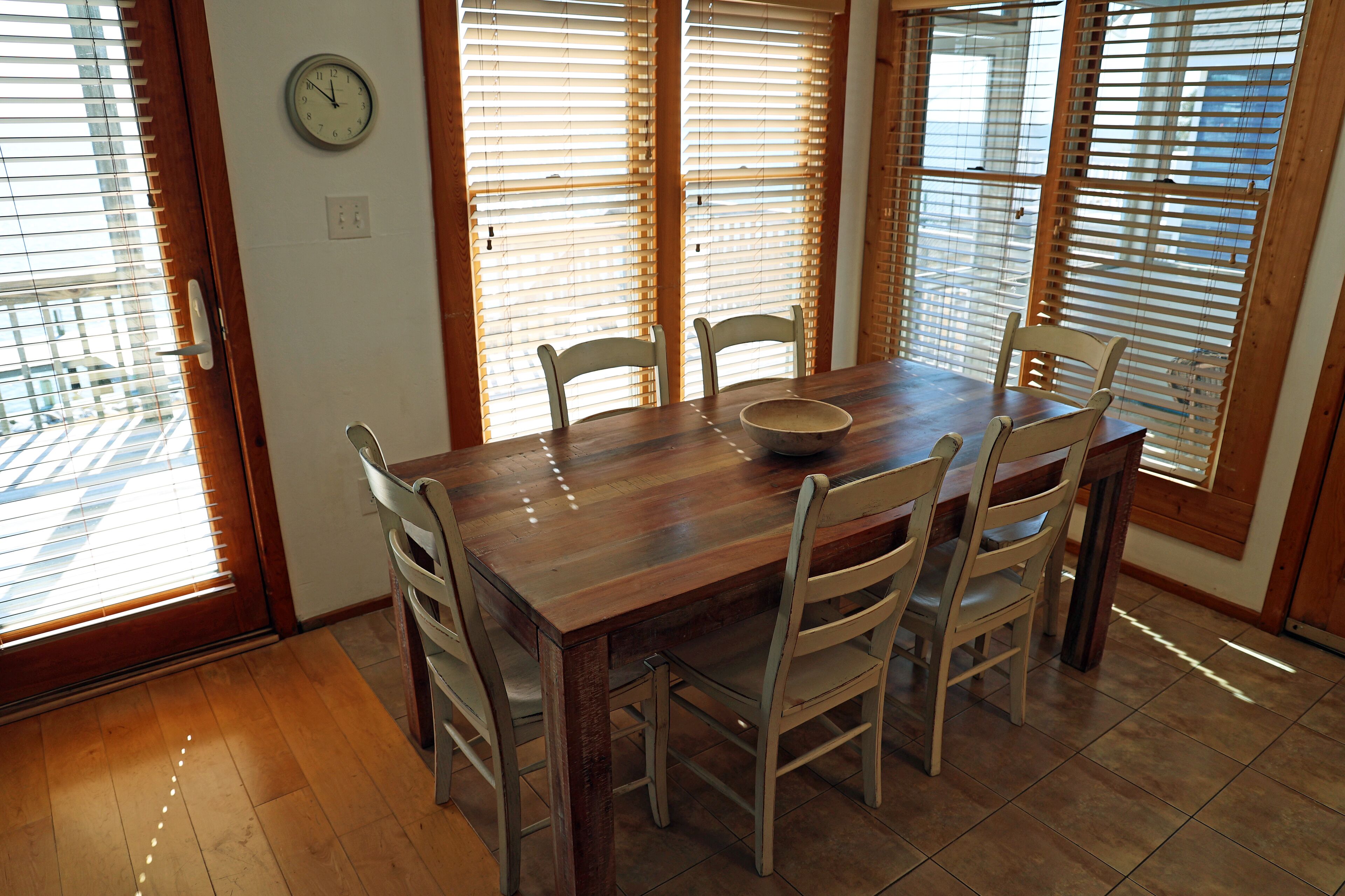 A dining room with a wooden table, four chairs, and a bowl.