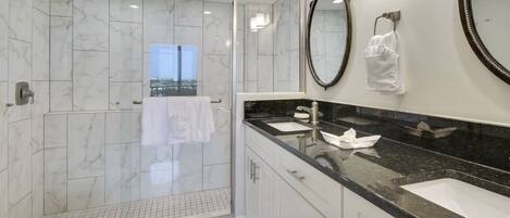 A modern bathroom with a glass-enclosed shower, a large mirror, and a vanity with a black countertop.