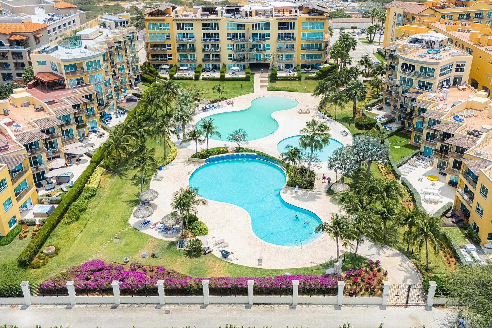 Resort com várias piscinas, paisagismo exuberante e diferentes estilos de construção.