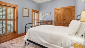 Quarto com cama, guarda-roupa de madeira, ventoinha no teto e janelas amplas.