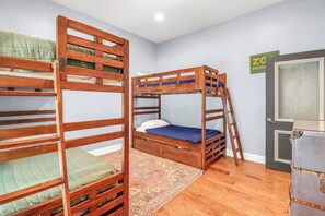 Een kamer met stapelbedden, een deur en een koffer.
