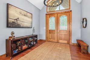 Ein Zimmer mit Holztür, Teppich, einer Bank, einem Stauraumschrank und einem Bild an der Wand.