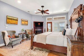 A bedroom with a large bed, a ceiling fan, a fireplace, and a telescope.