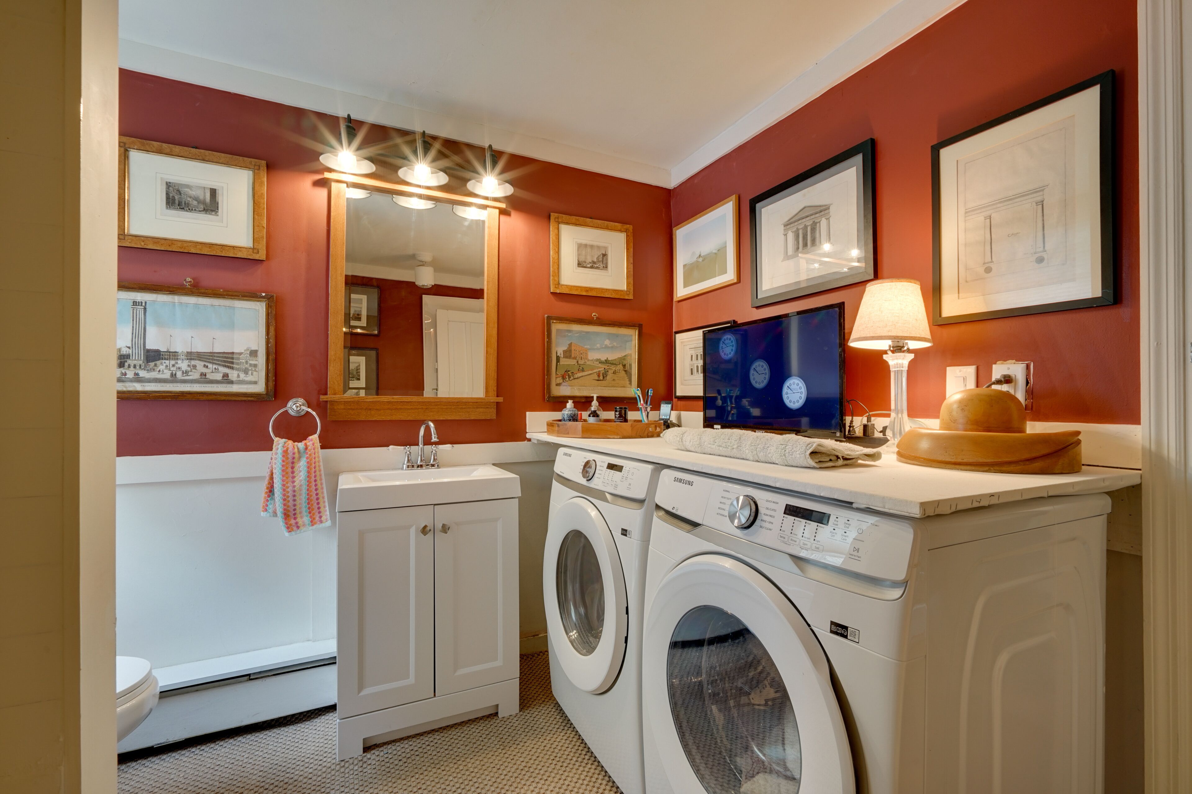A laundry room with a washing machine, dryer, sink, and a mirror.