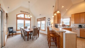 A spacious kitchen with wooden cabinets, a large island, and a dining area with a view of the landscape.