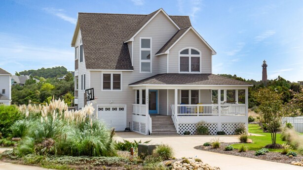 A two-story house with a front porch, a covered entryway, and a landscaped front yard.