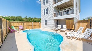 A swimming pool with lounge chairs and a wooden fence.