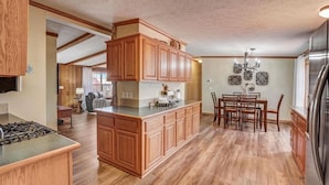 Una cocina amplia con armarios de madera, una isla central y un comedor con candelabro.