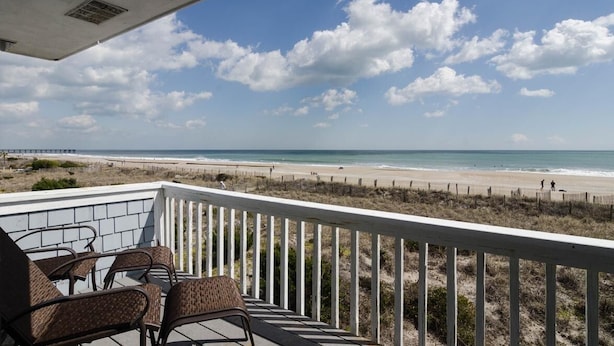 Ein Balkon mit Korbstühlen mit Blick auf einen Strand.