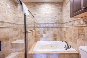 Un baño con bañera, cabina de ducha de vidrio y retrete.