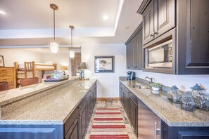 A modern kitchen with dark cabinetry, granite countertops, and built-in appliances.