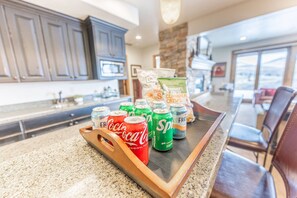 Una encimera de cocina con una bandeja que contiene latas de refresco y una bolsa de aperitivos.
