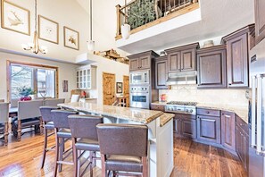 A spacious kitchen with dark wood cabinets, a central island with bar stools, and a large window providing natural light.