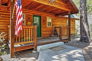 Cozy cabin with a welcoming porch and a large tree nearby.