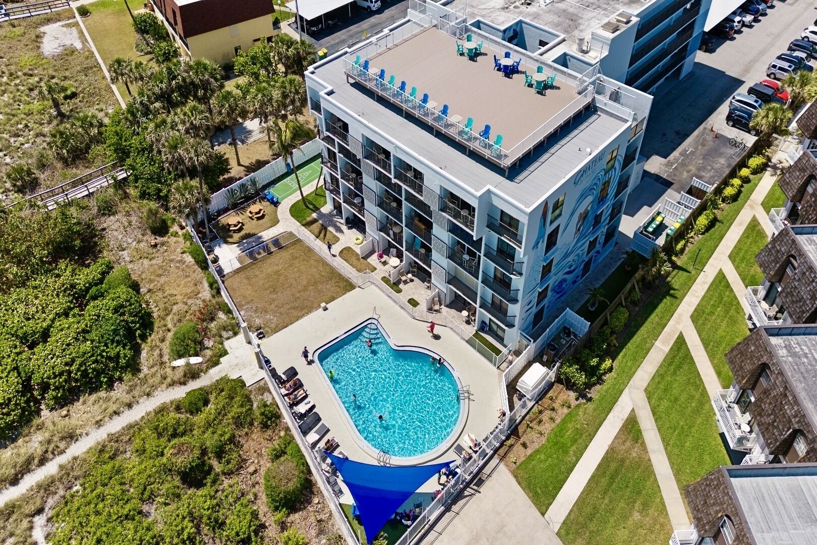 Un hotel de diverses plantes amb una piscina al terrat, zones d'estar a l'aire lliure i una zona enjardinada.