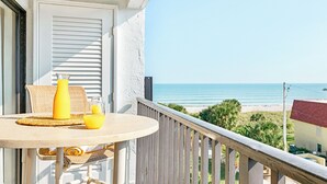 Un balcón con una mesa preparada para dos personas, con vista a la playa.