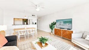 Una sala moderna con comedor, televisor y ventilador de techo.