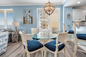 Relax in this stylish living room with a glass-top dining table, comfortable sofa, and ornate chandelier.