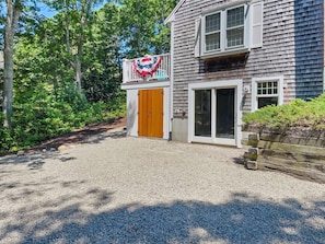 A two-story house with a gravel driveway, a wooden door, and a large window.