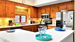 Una cucina moderna con mobili in legno, elettrodomestici in acciaio inossidabile e un'isola centrale con bicchieri e piatti.