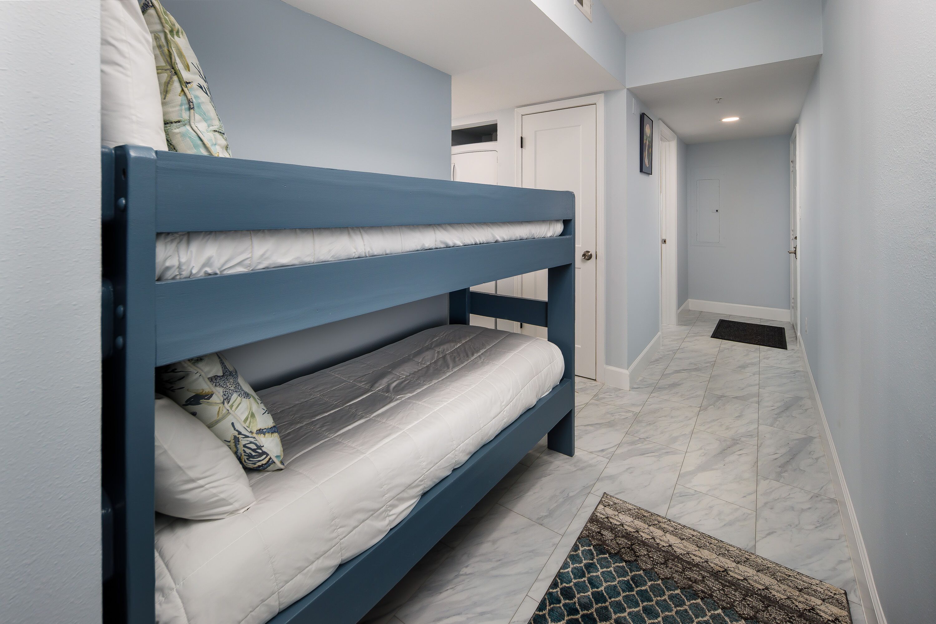 Una cama litera en un pasillo con una puerta y un ventanal pequeño.