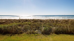 A beach with a fence in the foreground and a clear sky. - ETW 1003: Sandy Toes - Where summer is a state of mind! (Fort Walton Beach)