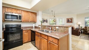 A modern kitchen with wooden cabinets, stainless steel appliances, and a granite countertop.