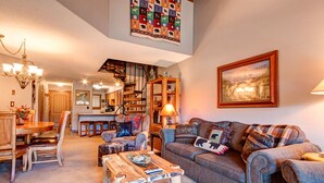 Ein gemütliches Wohnzimmer mit Kamin, einem Essbereich und einer Treppe, die zu einem Schlafzimmerboden führt.