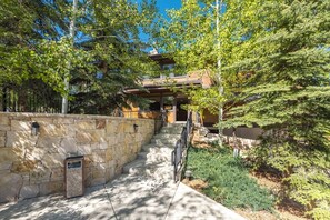 A stone pathway leading to a building with a wooden facade and a balcony.
