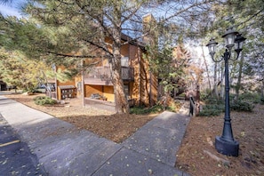 A two-story building with a balcony, surrounded by trees and a paved walkway.