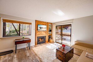 A living room with a fireplace, a sofa, a coffee table, and a large window.