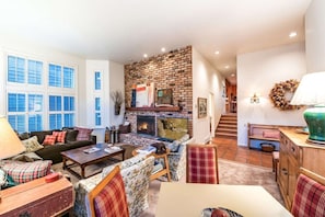A spacious living room with a fireplace, a sofa, a coffee table, and a dining area.
