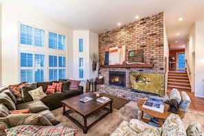 A living room with a fireplace, a sofa, a coffee table, and a television.