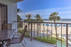 A balcony with a view of the beach, including palm trees and umbrellas. - Chic Myrtle Beach Seaside Escape w/ Pool Access! (Myrtle Beach)