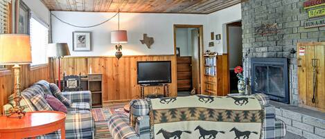 A cozy living room with a plaid sofa, a television, and a fireplace.
