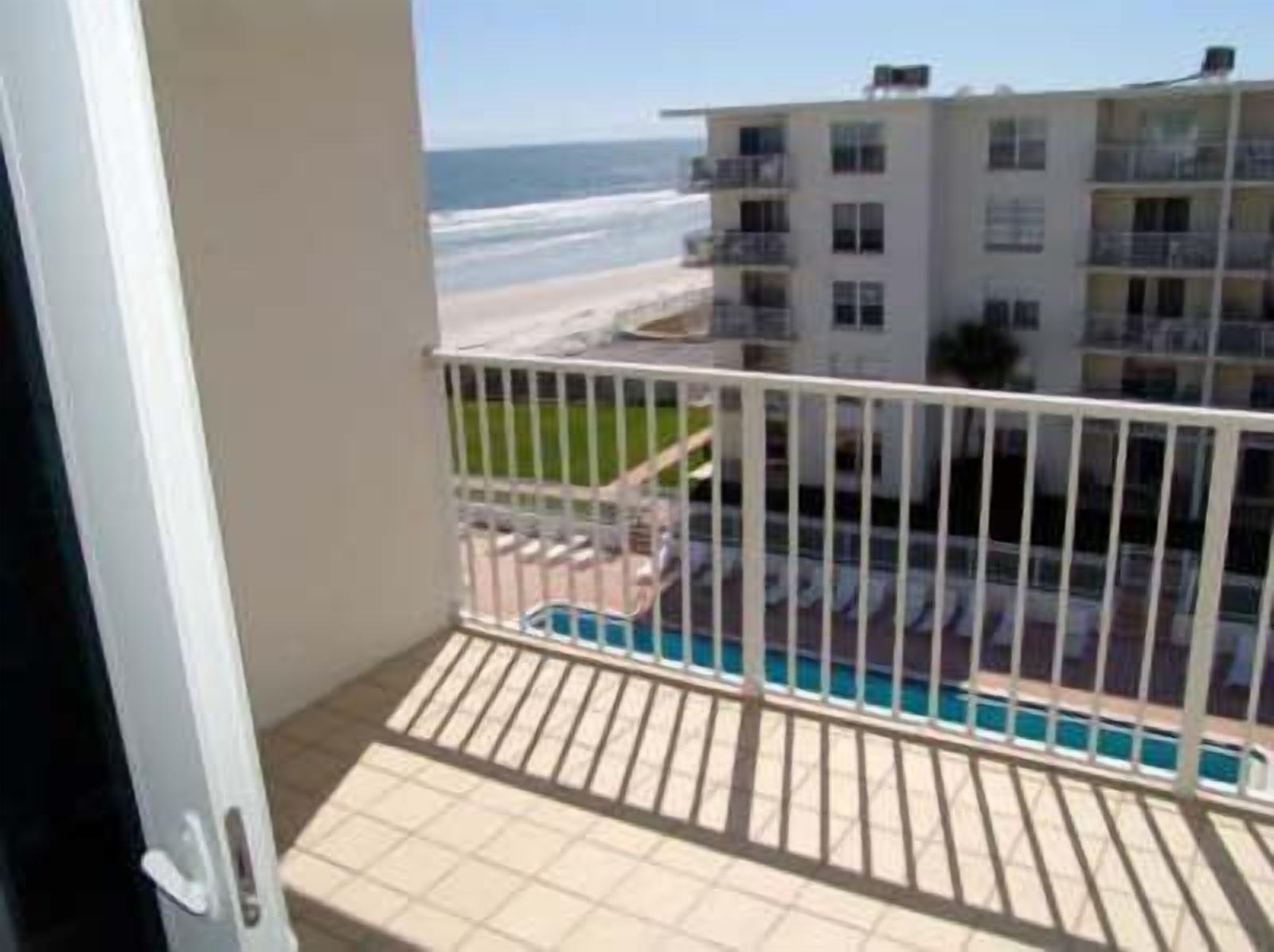 Un balcón con vista a la playa y una piscina.