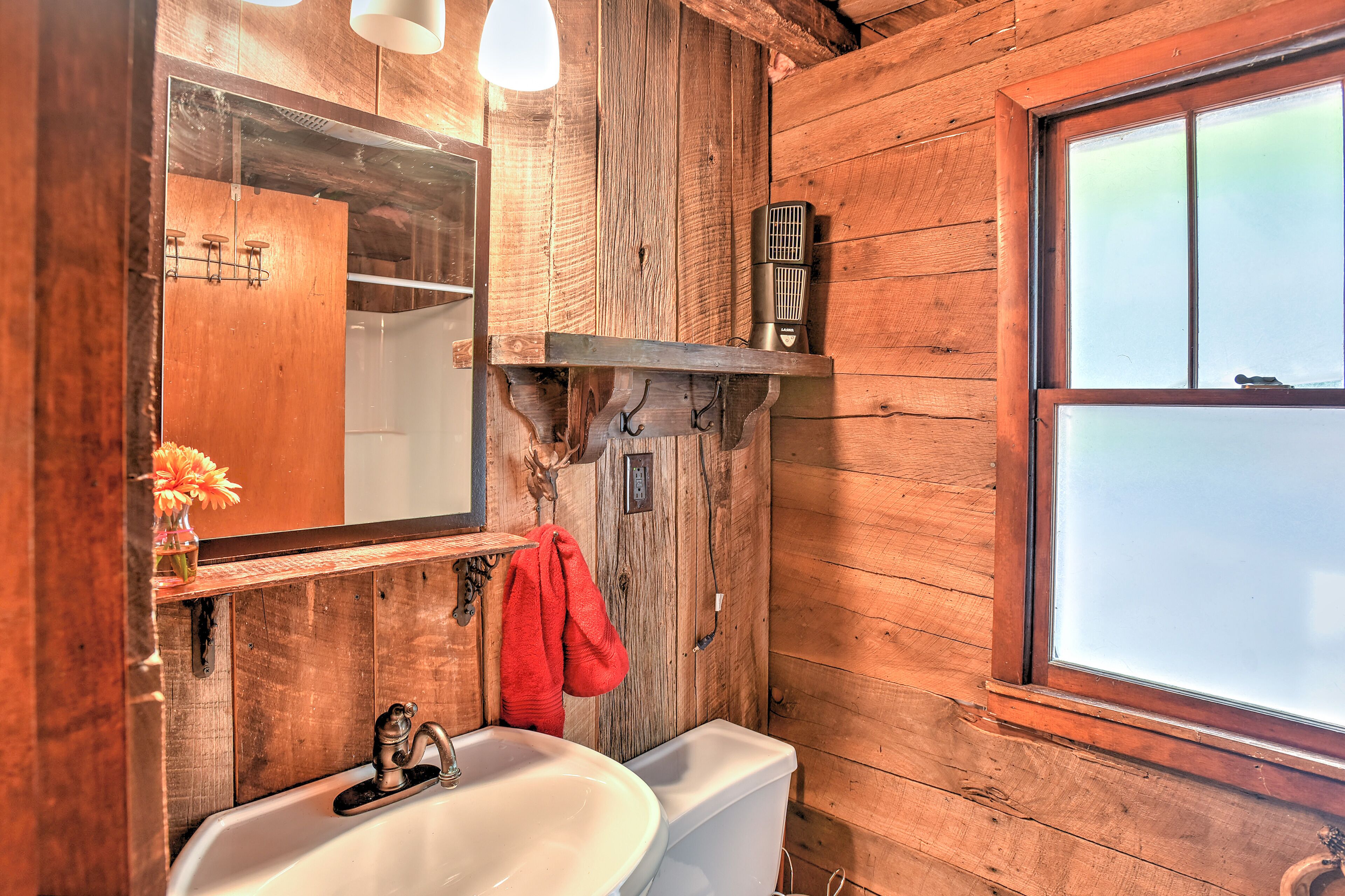 A rustic wooden bathroom with a sink, mirror, and towel rack.