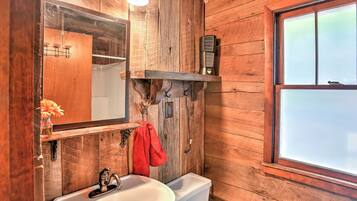 A rustic wooden bathroom with a sink, mirror, and towel rack.