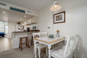 Um interior limpo e claro com cozinha, banquetas de madeira e mesa de jantar.
